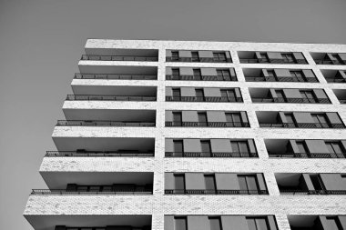 Güneş ışınları kentsel binalar üzerinde ışık etkisi yaratıyor. Düz binaları olan modern bir apartman dairesi. Yeni lüks ev ve kompleksin ayrıntıları. Siyah ve beyaz.