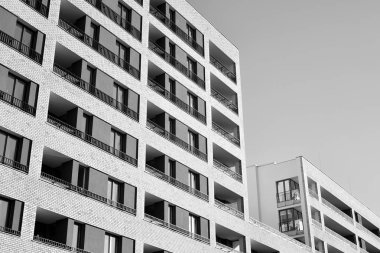 Güneş ışınları kentsel binalar üzerinde ışık etkisi yaratıyor. Düz binaları olan modern bir apartman dairesi. Yeni lüks ev ve kompleksin ayrıntıları. Siyah ve beyaz.