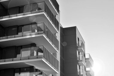 Güneş ışınları kentsel binalar üzerinde ışık etkisi yaratıyor. Düz binaları olan modern bir apartman dairesi. Yeni lüks ev ve kompleksin ayrıntıları. Siyah ve beyaz.