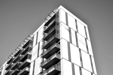 Güneş ışınları kentsel binalar üzerinde ışık etkisi yaratıyor. Düz binaları olan modern bir apartman dairesi. Yeni lüks ev ve kompleksin ayrıntıları. Siyah ve beyaz.