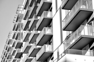 Güneş ışınları kentsel binalar üzerinde ışık etkisi yaratıyor. Düz binaları olan modern bir apartman dairesi. Yeni lüks ev ve kompleksin ayrıntıları. Siyah ve beyaz.