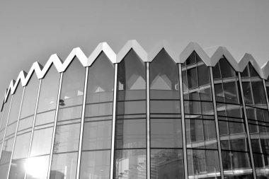 Güneş ışığı günbatımında kentsel binalar üzerinde ışık etkisi yaratır. Modern ofis inşaatı, güneş ışığıyla kaplı cam yüzey. İş geçmişi. Siyah ve beyaz.
