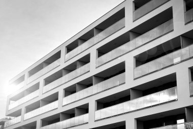 Güneş ışınları kentsel binalar üzerinde ışık etkisi yaratıyor. Düz binaları olan modern bir apartman dairesi. Yeni lüks ev ve kompleksin ayrıntıları. Siyah ve beyaz.