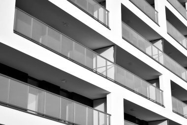 Güneş ışınları kentsel binalar üzerinde ışık etkisi yaratıyor. Düz binaları olan modern bir apartman dairesi. Yeni lüks ev ve kompleksin ayrıntıları. Siyah ve beyaz.