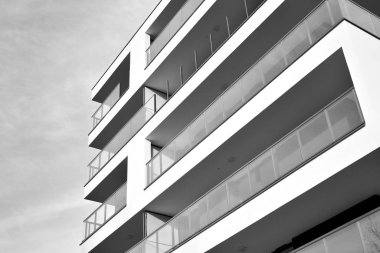 Güneş ışınları kentsel binalar üzerinde ışık etkisi yaratıyor. Düz binaları olan modern bir apartman dairesi. Yeni lüks ev ve kompleksin ayrıntıları. Siyah ve beyaz.