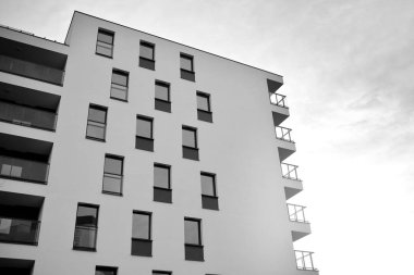 Güneş ışınları kentsel binalar üzerinde ışık etkisi yaratıyor. Düz binaları olan modern bir apartman dairesi. Yeni lüks ev ve kompleksin ayrıntıları. Siyah ve beyaz.