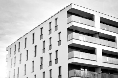 Güneş ışınları kentsel binalar üzerinde ışık etkisi yaratıyor. Düz binaları olan modern bir apartman dairesi. Yeni lüks ev ve kompleksin ayrıntıları. Siyah ve beyaz.