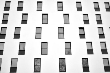 Güneş ışınları kentsel binalar üzerinde ışık etkisi yaratıyor. Düz binaları olan modern bir apartman dairesi. Yeni lüks ev ve kompleksin ayrıntıları. Siyah ve beyaz.