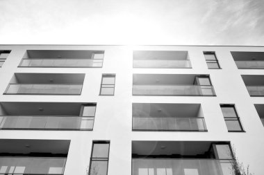 Güneş ışınları kentsel binalar üzerinde ışık etkisi yaratıyor. Düz binaları olan modern bir apartman dairesi. Yeni lüks ev ve kompleksin ayrıntıları. Siyah ve beyaz.