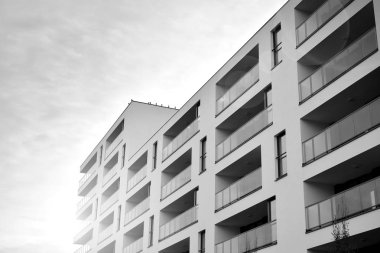 Güneş ışınları kentsel binalar üzerinde ışık etkisi yaratıyor. Düz binaları olan modern bir apartman dairesi. Yeni lüks ev ve kompleksin ayrıntıları. Siyah ve beyaz.