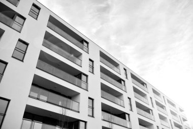 Güneş ışınları kentsel binalar üzerinde ışık etkisi yaratıyor. Düz binaları olan modern bir apartman dairesi. Yeni lüks ev ve kompleksin ayrıntıları. Siyah ve beyaz.