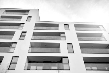 Güneş ışınları kentsel binalar üzerinde ışık etkisi yaratıyor. Düz binaları olan modern bir apartman dairesi. Yeni lüks ev ve kompleksin ayrıntıları. Siyah ve beyaz.