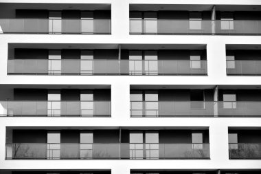 Güneş ışınları kentsel binalar üzerinde ışık etkisi yaratıyor. Düz binaları olan modern bir apartman dairesi. Yeni lüks ev ve kompleksin ayrıntıları. Siyah ve beyaz.