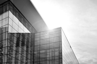 Güneş ışığı günbatımında kentsel binalar üzerinde ışık etkisi yaratır. Modern ofis inşaatı, güneş ışığıyla kaplı cam yüzey. İş geçmişi. Siyah ve beyaz.