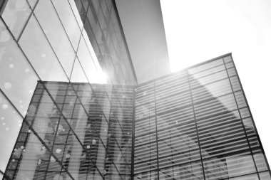 Güneş ışığı günbatımında kentsel binalar üzerinde ışık etkisi yaratır. Modern ofis inşaatı, güneş ışığıyla kaplı cam yüzey. İş geçmişi. Siyah ve beyaz.