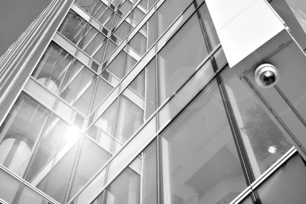 Sun rays light effects on urban buildings in sunset. Modern office building detail, glass surface with sunlight. Business background. Black and white.