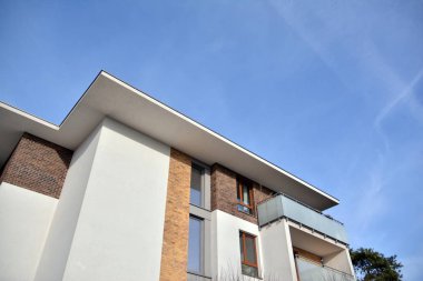 Mavi gökyüzü olan güneşli bir günde modern apartman binaları. Modern bir apartmanın ön cephesi. Güneş ışığıyla kaplı cam yüzey..