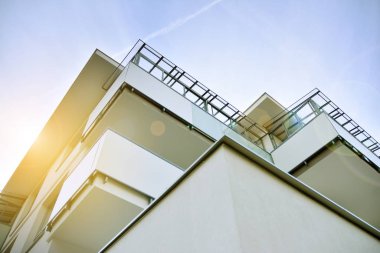 Mavi gökyüzü olan güneşli bir günde modern apartman binaları. Modern bir apartmanın ön cephesi. Güneş ışığıyla kaplı cam yüzey..