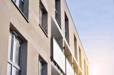 Mavi gökyüzü olan güneşli bir günde modern apartman binaları. Modern bir apartmanın ön cephesi. Güneş ışığıyla kaplı cam yüzey..