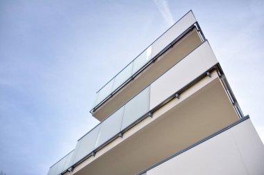 Mavi gökyüzü olan güneşli bir günde modern apartman binaları. Modern bir apartmanın ön cephesi. Güneş ışığıyla kaplı cam yüzey..