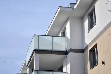 Mavi gökyüzü olan güneşli bir günde modern apartman binaları. Modern bir apartmanın ön cephesi. Güneş ışığıyla kaplı cam yüzey..