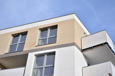 Mavi gökyüzü olan güneşli bir günde modern apartman binaları. Modern bir apartmanın ön cephesi. Güneş ışığıyla kaplı cam yüzey..