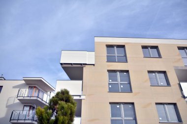Mavi gökyüzü olan güneşli bir günde modern apartman binaları. Modern bir apartmanın ön cephesi. Güneş ışığıyla kaplı cam yüzey..
