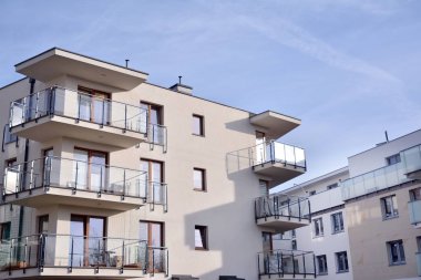 Mavi gökyüzü olan güneşli bir günde modern apartman binaları. Modern bir apartmanın ön cephesi. Güneş ışığıyla kaplı cam yüzey..