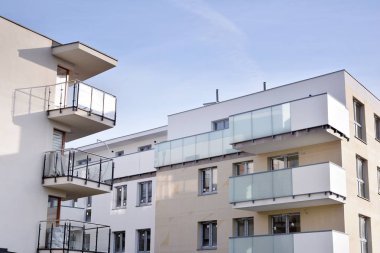 Mavi gökyüzü olan güneşli bir günde modern apartman binaları. Modern bir apartmanın ön cephesi. Güneş ışığıyla kaplı cam yüzey..