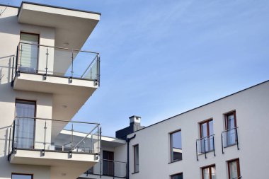 Mavi gökyüzü olan güneşli bir günde modern apartman binaları. Modern bir apartmanın ön cephesi. Güneş ışığıyla kaplı cam yüzey..