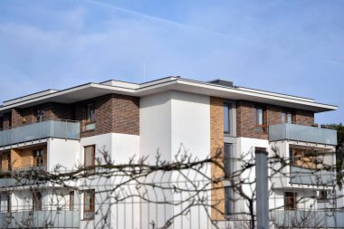 Mavi gökyüzü olan güneşli bir günde modern apartman binaları. Modern bir apartmanın ön cephesi. Güneş ışığıyla kaplı cam yüzey..