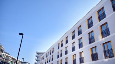 Gündüz gözüyle modern yerleşim yerinin dış tarafında. Mavi gökyüzü olan güneşli bir günde modern apartman binaları. Modern bir apartmanın cephesi