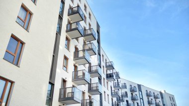 Gündüz gözüyle modern yerleşim yerinin dış tarafında. Mavi gökyüzü olan güneşli bir günde modern apartman binaları. Modern bir apartmanın cephesi