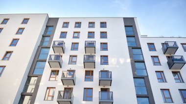 Gündüz gözüyle modern yerleşim yerinin dış tarafında. Mavi gökyüzü olan güneşli bir günde modern apartman binaları. Modern bir apartmanın cephesi