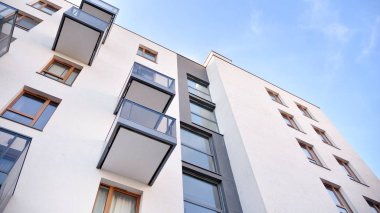 Gündüz gözüyle modern yerleşim yerinin dış tarafında. Mavi gökyüzü olan güneşli bir günde modern apartman binaları. Modern bir apartmanın cephesi