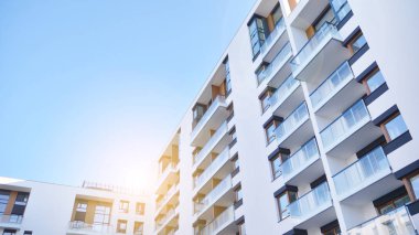 Modern multi story building being lit by the setting sun at afternoon. New apartment house residential building outdoor concept.