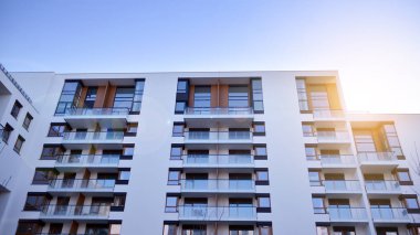 Modern multi story building being lit by the setting sun at afternoon. New apartment house residential building outdoor concept.