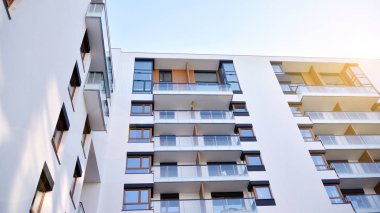 Modern multi story building being lit by the setting sun at afternoon. New apartment house residential building outdoor concept.