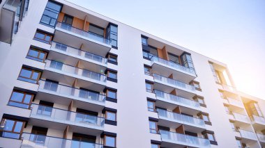 Modern multi story building being lit by the setting sun at afternoon. New apartment house residential building outdoor concept.