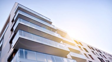 Modern multi story building being lit by the setting sun at afternoon. New apartment house residential building outdoor concept.