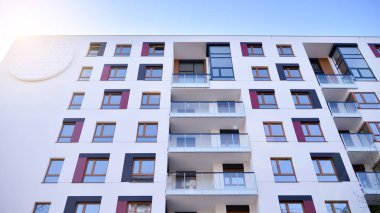 Modern multi story building being lit by the setting sun at afternoon. New apartment house residential building outdoor concept.