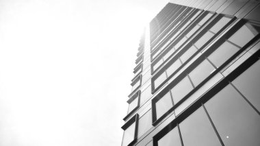 Güneş ışığı günbatımında kentsel binalar üzerinde ışık etkisi yaratır. Modern ofis inşaatı, güneş ışığıyla kaplı cam yüzey. İş geçmişi. Siyah ve beyaz.