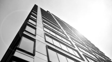 Güneş ışığı günbatımında kentsel binalar üzerinde ışık etkisi yaratır. Modern ofis inşaatı, güneş ışığıyla kaplı cam yüzey. İş geçmişi. Siyah ve beyaz.