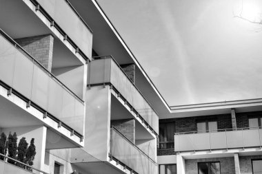 Güneş ışınları kentsel binalar üzerinde ışık etkisi yaratıyor. Düz binaları olan modern bir apartman dairesi. Yeni lüks ev ve kompleksin ayrıntıları. Siyah ve beyaz.