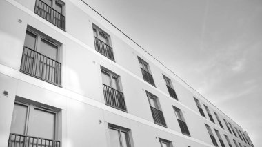 Güneş ışınları kentsel binalar üzerinde ışık etkisi yaratıyor. Düz binaları olan modern bir apartman dairesi. Yeni lüks ev ve kompleksin ayrıntıları. Siyah ve beyaz.