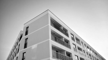 Güneş ışınları kentsel binalar üzerinde ışık etkisi yaratıyor. Düz binaları olan modern bir apartman dairesi. Yeni lüks ev ve kompleksin ayrıntıları. Siyah ve beyaz.