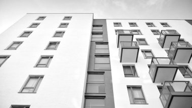 Güneş ışınları kentsel binalar üzerinde ışık etkisi yaratıyor. Düz binaları olan modern bir apartman dairesi. Yeni lüks ev ve kompleksin ayrıntıları. Siyah ve beyaz.