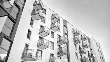 Güneş ışınları kentsel binalar üzerinde ışık etkisi yaratıyor. Düz binaları olan modern bir apartman dairesi. Yeni lüks ev ve kompleksin ayrıntıları. Siyah ve beyaz.