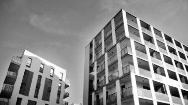 Güneş ışınları kentsel binalar üzerinde ışık etkisi yaratıyor. Düz binaları olan modern bir apartman dairesi. Yeni lüks ev ve kompleksin ayrıntıları. Siyah ve beyaz.