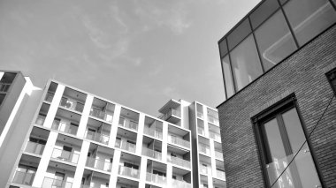 Güneş ışınları kentsel binalar üzerinde ışık etkisi yaratıyor. Düz binaları olan modern bir apartman dairesi. Yeni lüks ev ve kompleksin ayrıntıları. Siyah ve beyaz.